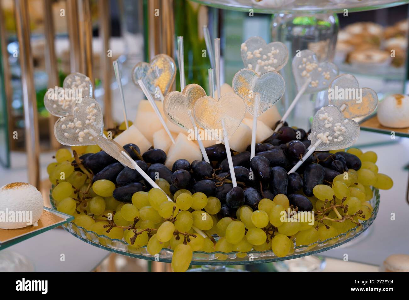 Elegante Dessertpräsentation mit herzförmigen Pops und lebhaftem Obst. Stockfoto