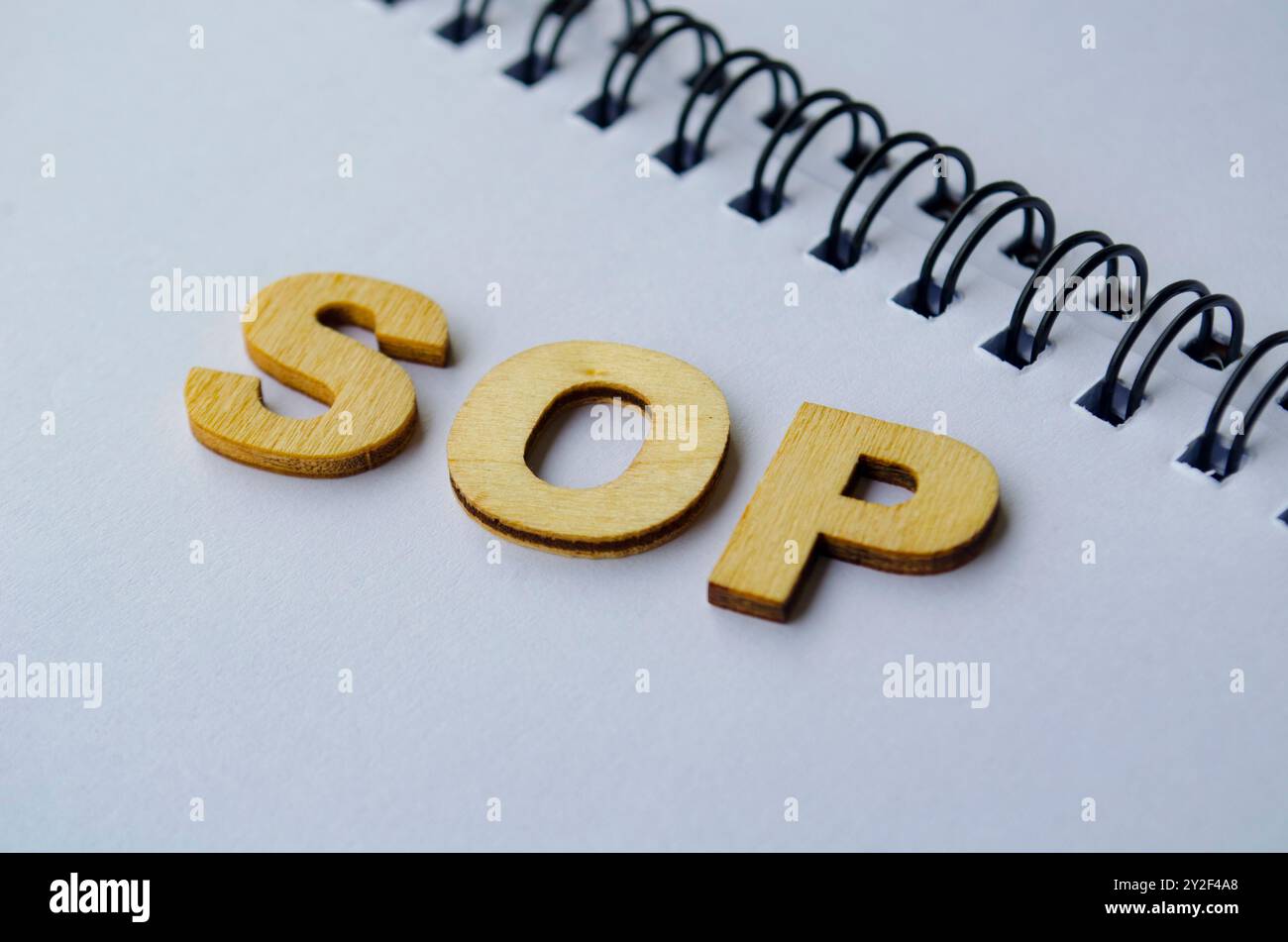 Draufsicht der SOP-Holzbuchstaben auf weißem Notizblock. Standardkonzept für Betriebsverfahren. Stockfoto