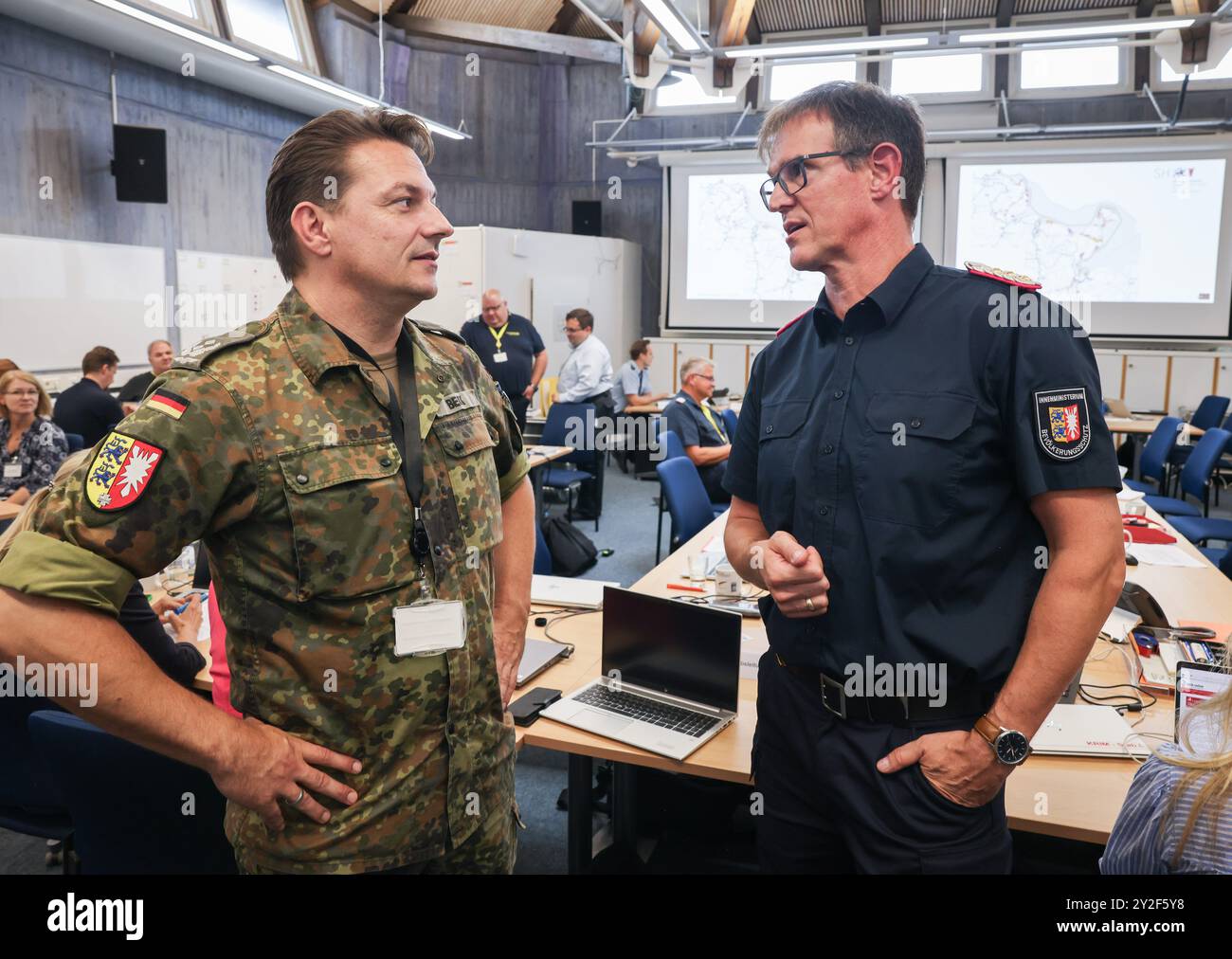Kiel, Deutschland. September 2024. Dirk Hundertmark (r), Leiter Krisenmanagement im Innenministerium, und Matthis Beck, Oberstleutnant der Bundeswehr, sprechen im Operationssaal während einer Pressekonferenz während der Planungsübung für das Krisenteam zum Szenario „Sturmflut in der Ostsee“. Katastrophenschutzbeamte bereiten sich noch immer auf den Einsatz vor, falls es zu einem schweren Sturmflut in der Ostsee kommt, wie es im Oktober mit einer Planübung in Kiel bis Donnerstag der Fall war. Quelle: Christian Charisius/dpa/Alamy Live News Stockfoto