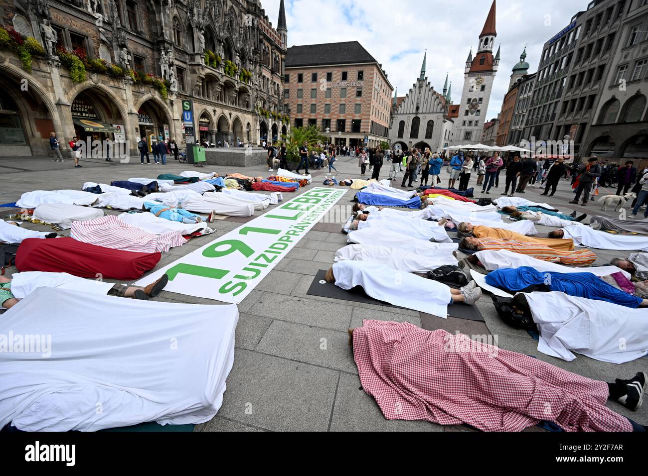 München, Deutschland. September 2024. Anlässlich des Welttages zur Suizidprävention liegen Teilnehmer einer Allianz von Krisen- und Beratungsdiensten auf dem Münchner Marienplatz in Blätter gewickelt, die die 191 Menschen repräsentieren, die 2022 in München durch Selbstmord starben. 2023 stieg diese Zahl auf 207 an. Quelle: Felix Hörhager/dpa/Alamy Live News Stockfoto