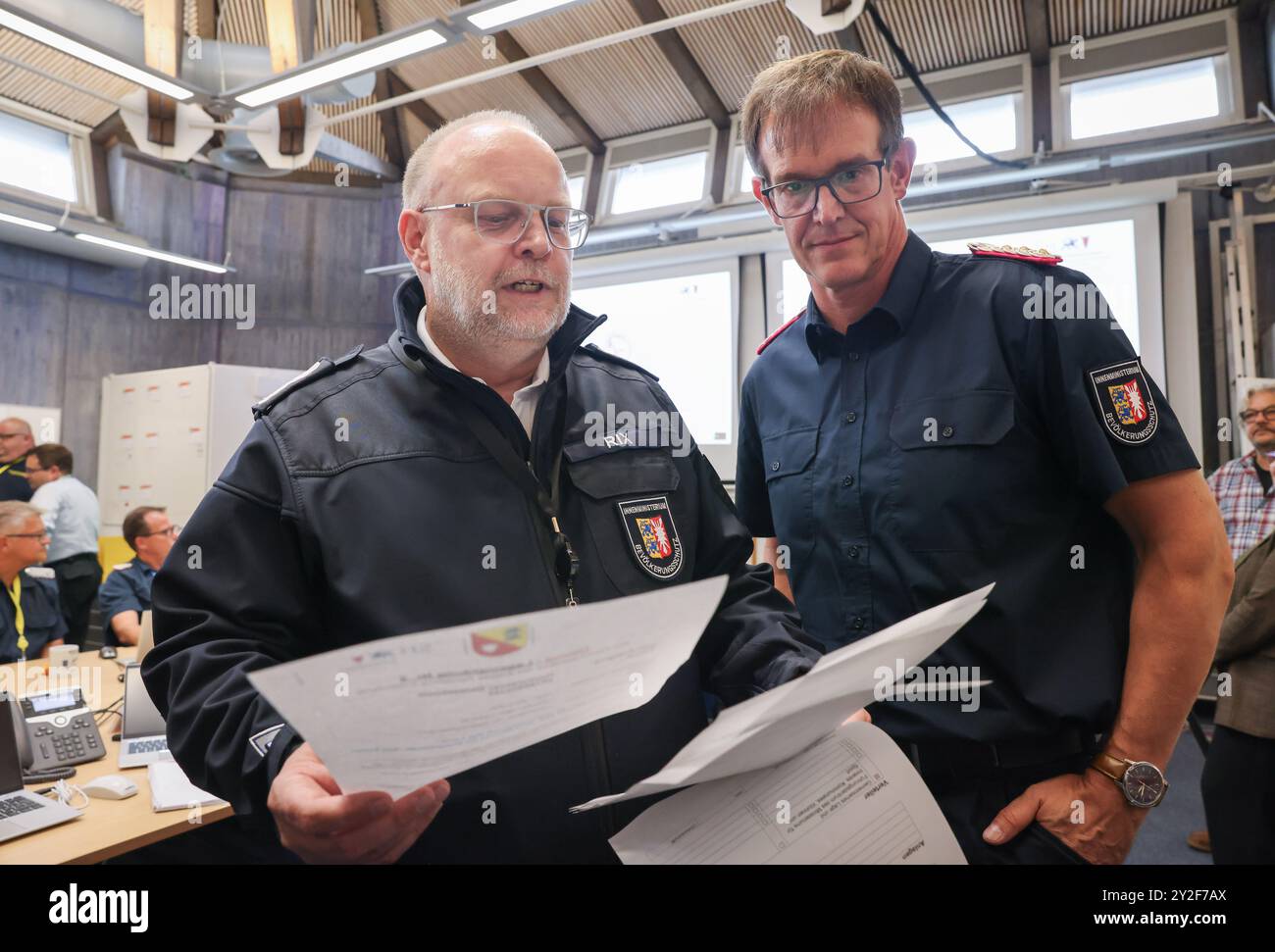 Kiel, Deutschland. September 2024. Dirk Hundertmark (r), Leiter des Referats Krisenmanagement im Innenministerium, und Svend Rix, stellvertretender Leiter des Referats Krisenmanagement und heutiger Übungsleiter, sprechen im Operationssaal bei einer Presseveranstaltung während der Planungsübung für das Krisenreferat zum Szenario "Sturmflut in der Ostsee". Mit einer Planungsübung bereiten sich Katastrophenschutzbeamte bis Donnerstag in Kiel auf den Einsatz im Falle einer schweren Sturmflut in der Ostsee wie im Oktober vor. Quelle: Christian Charisius/dpa/Alamy Live News Stockfoto