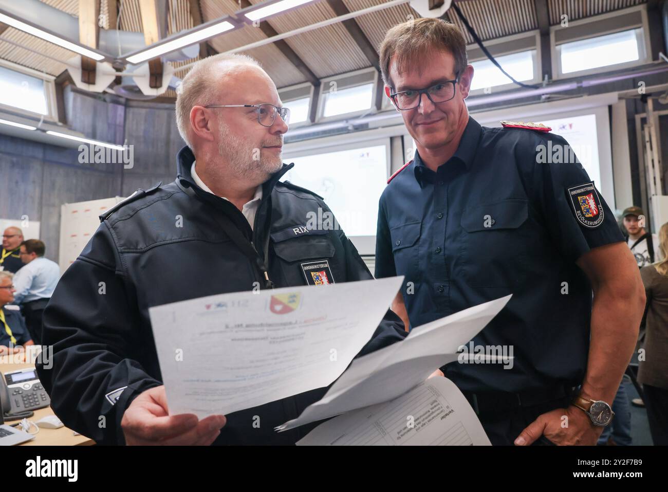 Kiel, Deutschland. September 2024. Dirk Hundertmark (r), Leiter des Referats Krisenmanagement im Innenministerium, und Svend Rix, stellvertretender Leiter des Referats Krisenmanagement und heutiger Übungsleiter, sprechen im Operationssaal bei einer Presseveranstaltung während der Planungsübung für das Krisenreferat zum Szenario "Sturmflut in der Ostsee". Mit einer Planungsübung bereiten sich Katastrophenschutzbeamte bis Donnerstag in Kiel auf den Einsatz im Falle einer schweren Sturmflut in der Ostsee wie im Oktober vor. Quelle: Christian Charisius/dpa/Alamy Live News Stockfoto