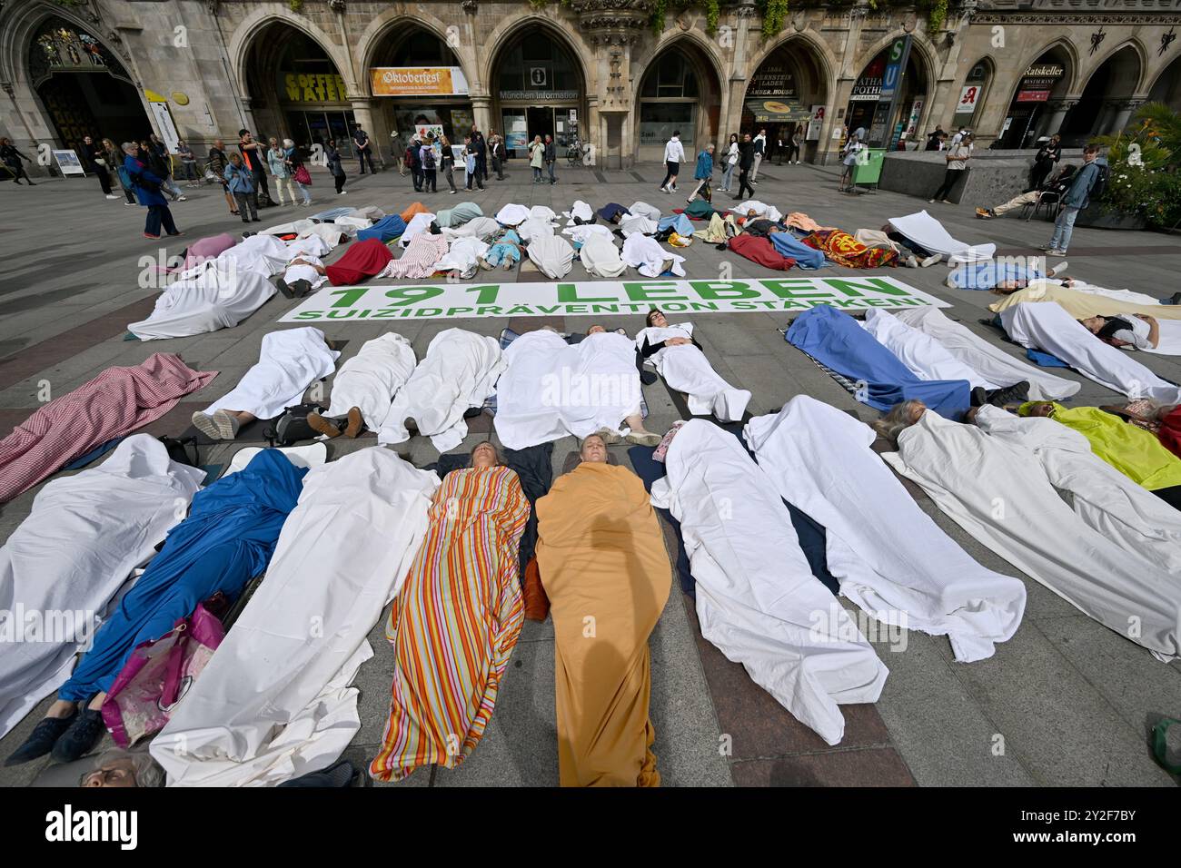München, Deutschland. September 2024. Anlässlich des Welttages zur Suizidprävention liegen Teilnehmer einer Allianz von Krisen- und Beratungsdiensten auf dem Münchner Marienplatz in Blätter gewickelt, die die 191 Menschen repräsentieren, die 2022 in München durch Selbstmord starben. 2023 stieg diese Zahl auf 207 an. Quelle: Felix Hörhager/dpa/Alamy Live News Stockfoto