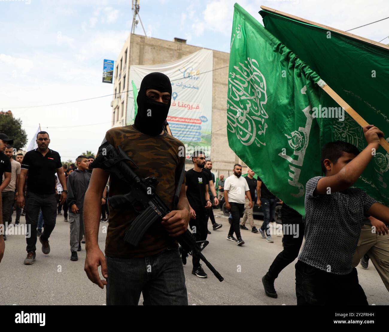 Jenin, Westjordanland, Palästina. 27. Oktober 2023. Ein palästinensischer Junge hält die Hamas-Flagge bei einer Beerdigung von drei palästinensischen jungen Männern, die von israelischen Truppen während eines israelischen Überfalls auf das Flüchtlingslager Dschenin am 27. Morgen getötet wurden. Abdullah Abu Al-Haija, Aysar al-Amer und Jawad Al-Turki wurden getötet und 12 weitere verwundet, nachdem während des Überfalls bewaffnete Zusammenstöße im Lager ausbrachen. Die Einheimischen sahen, wie israelische Truppen das Feuer auf Krankenwagen öffneten, die versuchten, den Verletzten zu helfen. Über 100 Palästinenser wurden getötet und Stockfoto