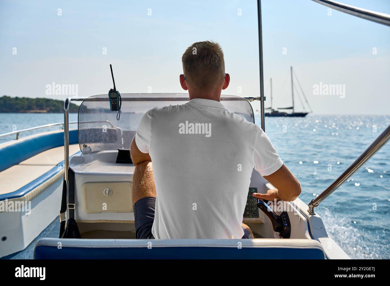 Porec, Istrien, Kroatien - 27. August 2024: Ein junger Mann steuert ein Motorboot auf dem klaren blauen Wasser der kroatischen Küste - perfekter Sommertag auf dem Meer *** ein junger Mann steuert ein Motorboot auf dem klaren, blauen Wasser der kroatischen Küste perfekter Sommertag auf dem Meer Stockfoto