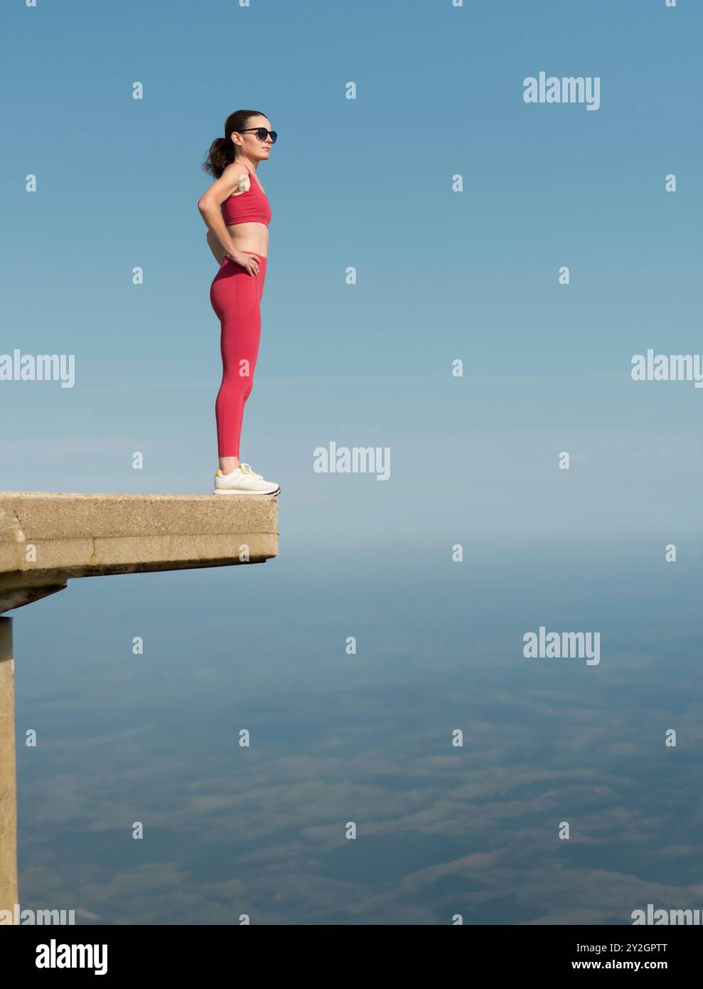 Sportliche Frau, die auf einem hohen Betongebäude steht und auf dem Konzept lebt Stockfoto