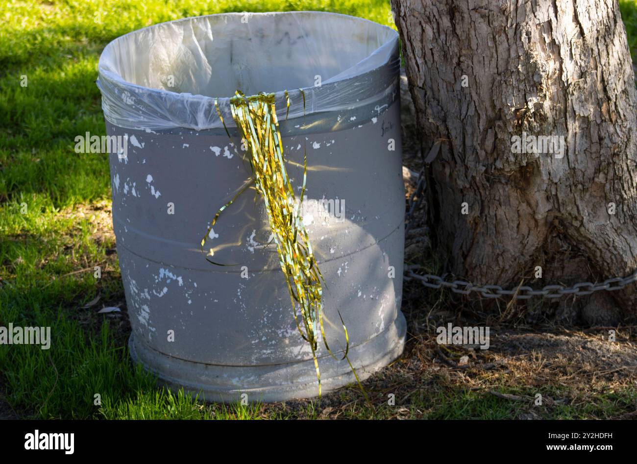 Goldene Party-Streamer, die im Abfalleimer im Freien weggeworfen werden Stockfoto