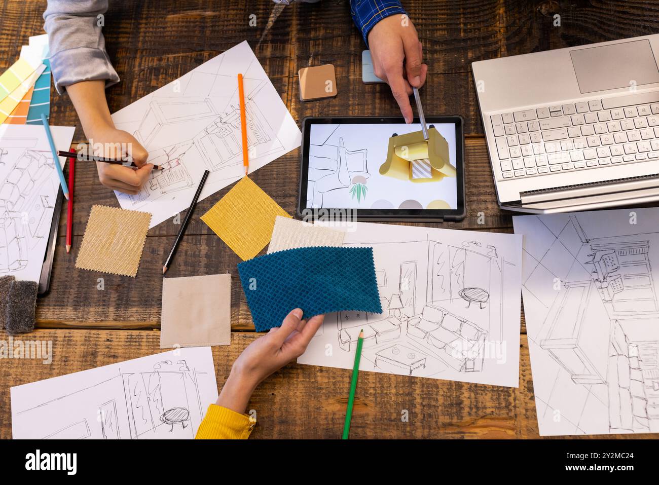 Im Büro ein vielfältiges Team, das Tablets, Stoffmuster und Skizzen auf dem Tisch verwendet Stockfoto