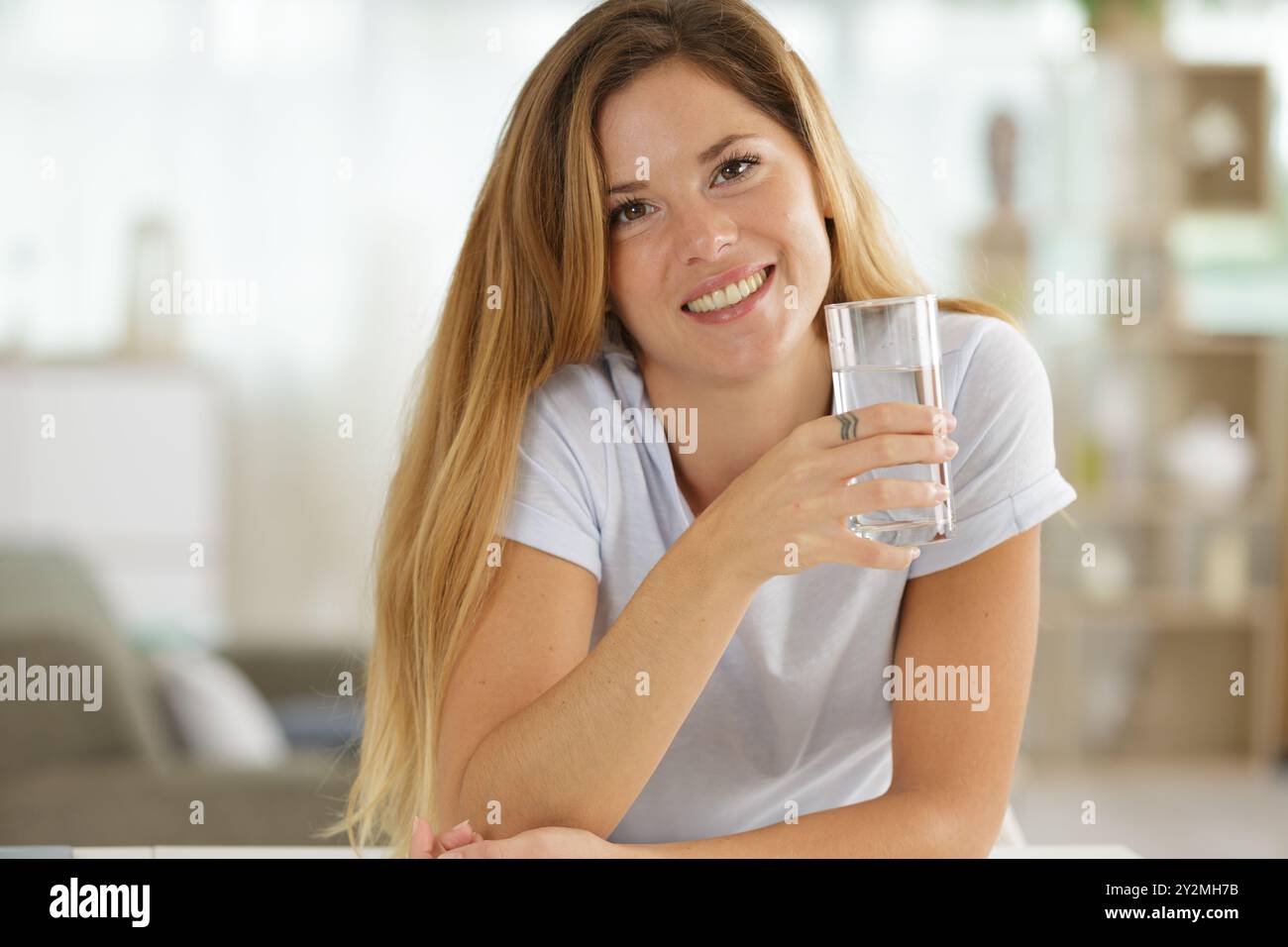 Junge gesunde Frau, die ein Glas Wasser hält Stockfoto