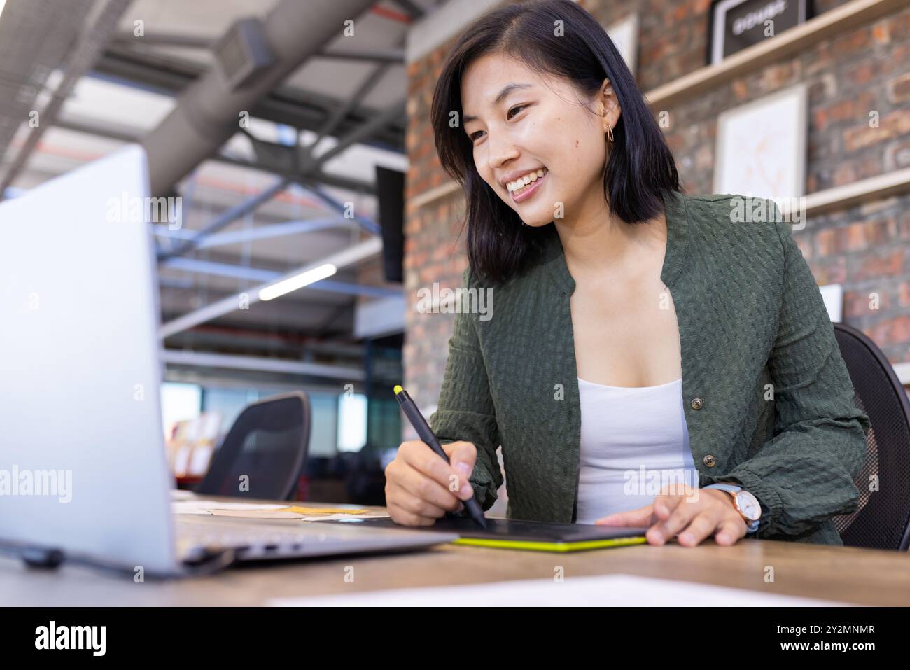 Mit digitalem Stift und Tablet arbeitet asiatische Frau am Laptop in modernen Büros Stockfoto