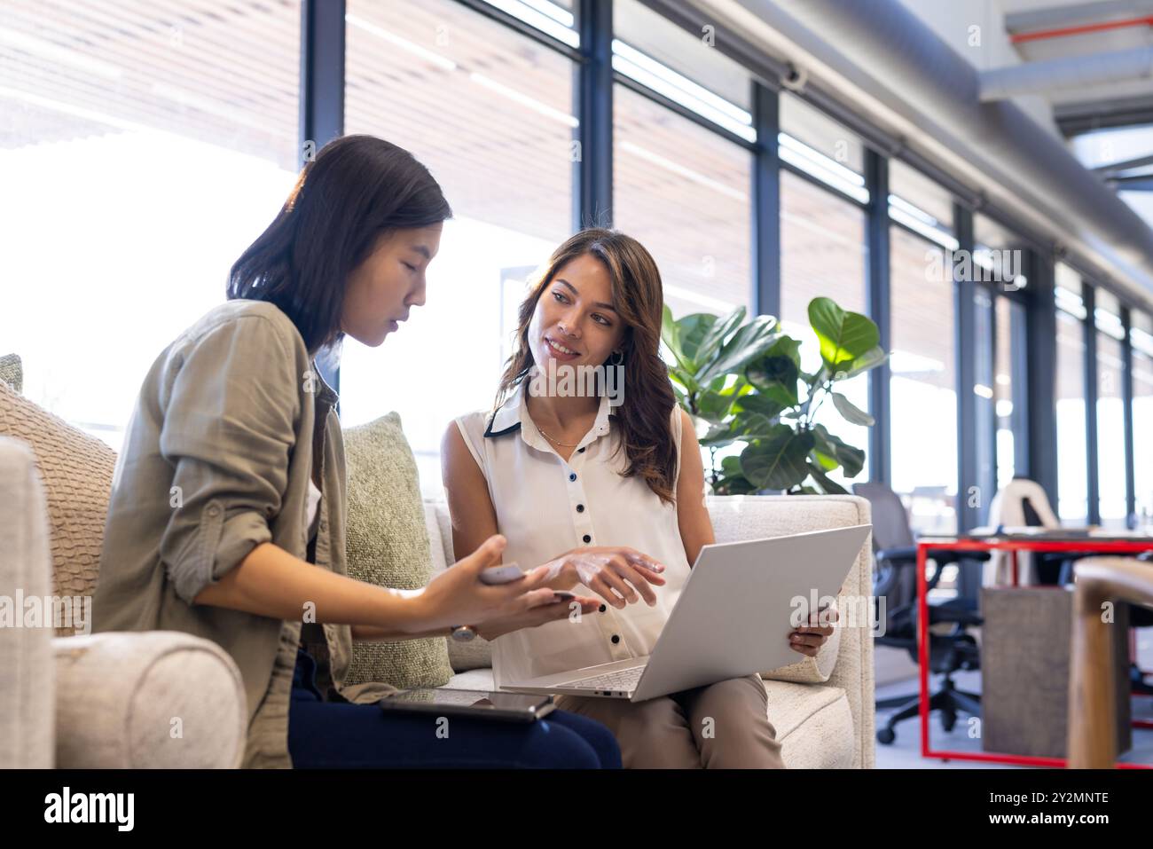 Diskutieren Ideen für die Innenarchitektur, verschiedene Frauen, die in modernen Büros mit Laptops zusammenarbeiten Stockfoto