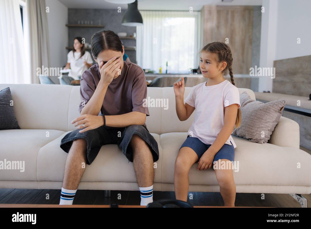 Der ältere Bruder hat ein wenig gezingelt, als seine jüngere Schwester auf das, was er im Fernsehen gesehen hat, reagiert hat. Unangenehme Situation Stockfoto