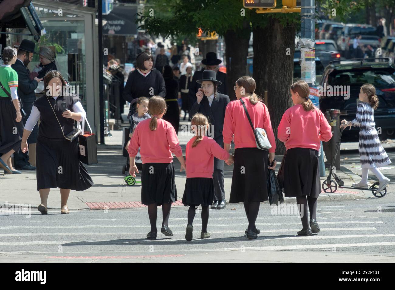 Eine Straßenszene mit 4 bescheiden gekleideten Schwestern mit derselben Kleidung und Frisur. Auf der Lee Avenue in Williamsburg, Brooklyn, New York. Stockfoto