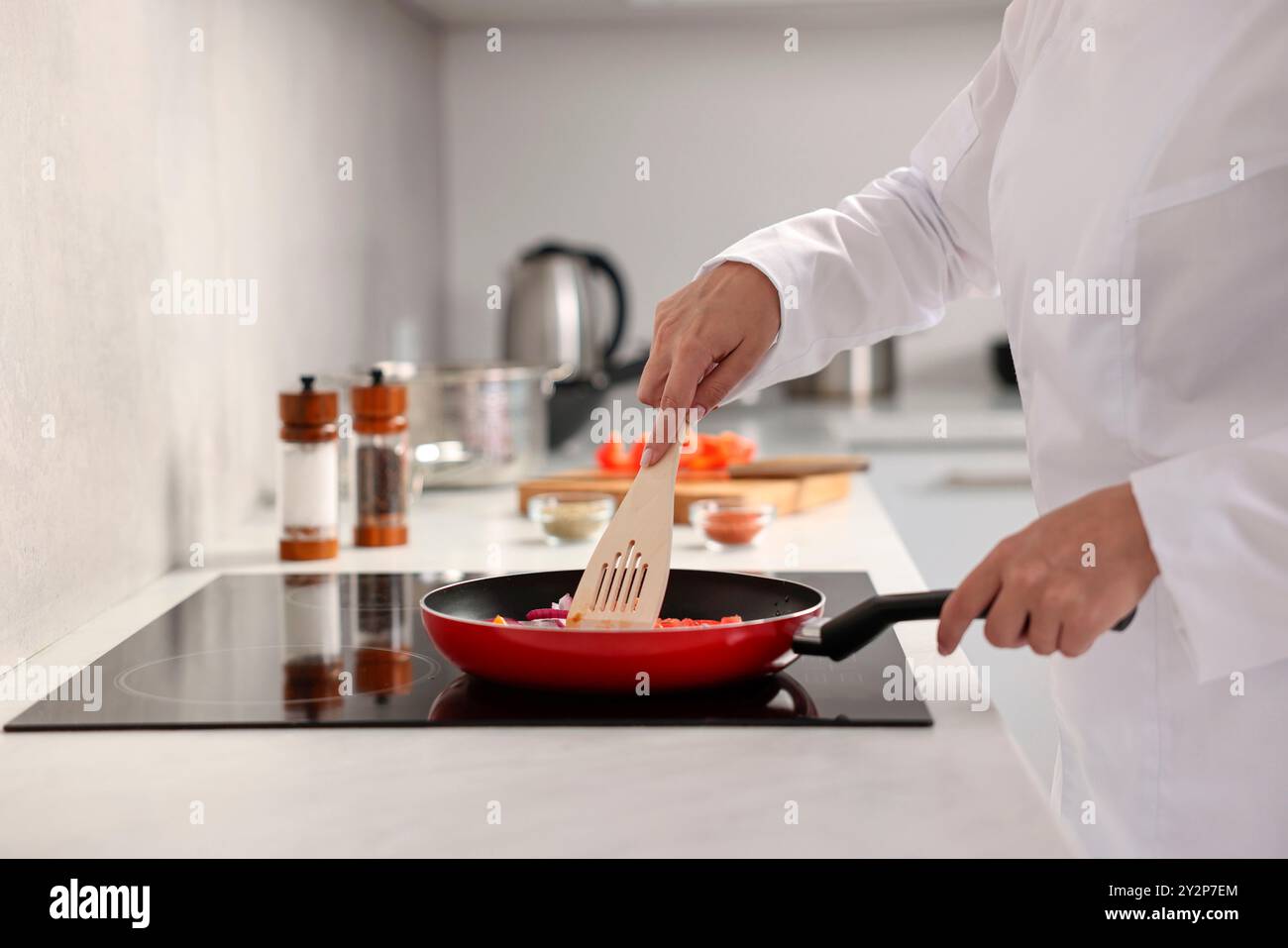 Professioneller Koch kocht köstliches Essen auf dem Herd in der Küche, Nahaufnahme Stockfoto