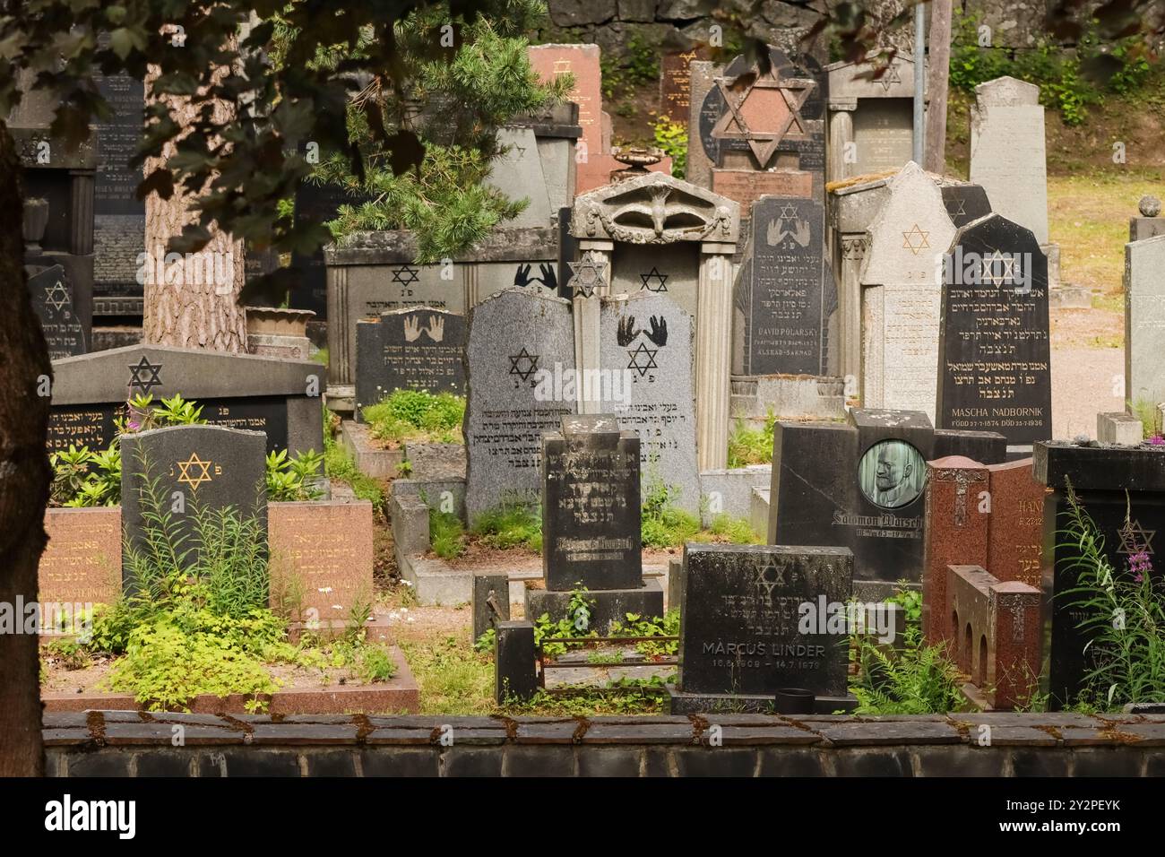 Ein alter jüdischer Friedhof in Hietaniemi, Helsinki. Mehrere Grabsteine haben hebräischen Text und jüdische Symbole. Ein bewölkter Tag im Juni 2024. Stockfoto