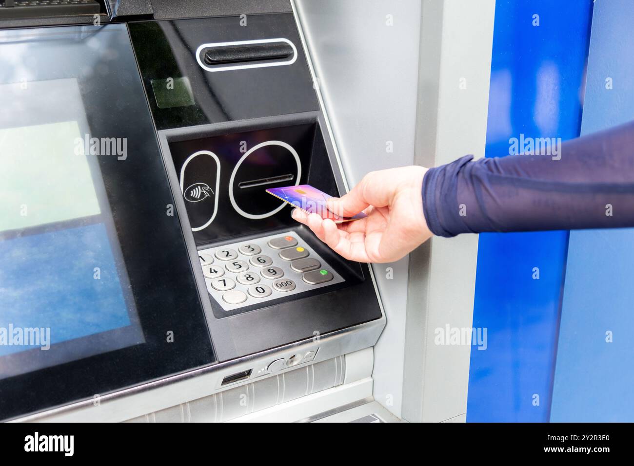 Eine Person verwendet eine kontaktlose Zahlungsmethode mit einer Debitkarte an einem Geldautomaten, die moderne Banktechnologie bietet Stockfoto