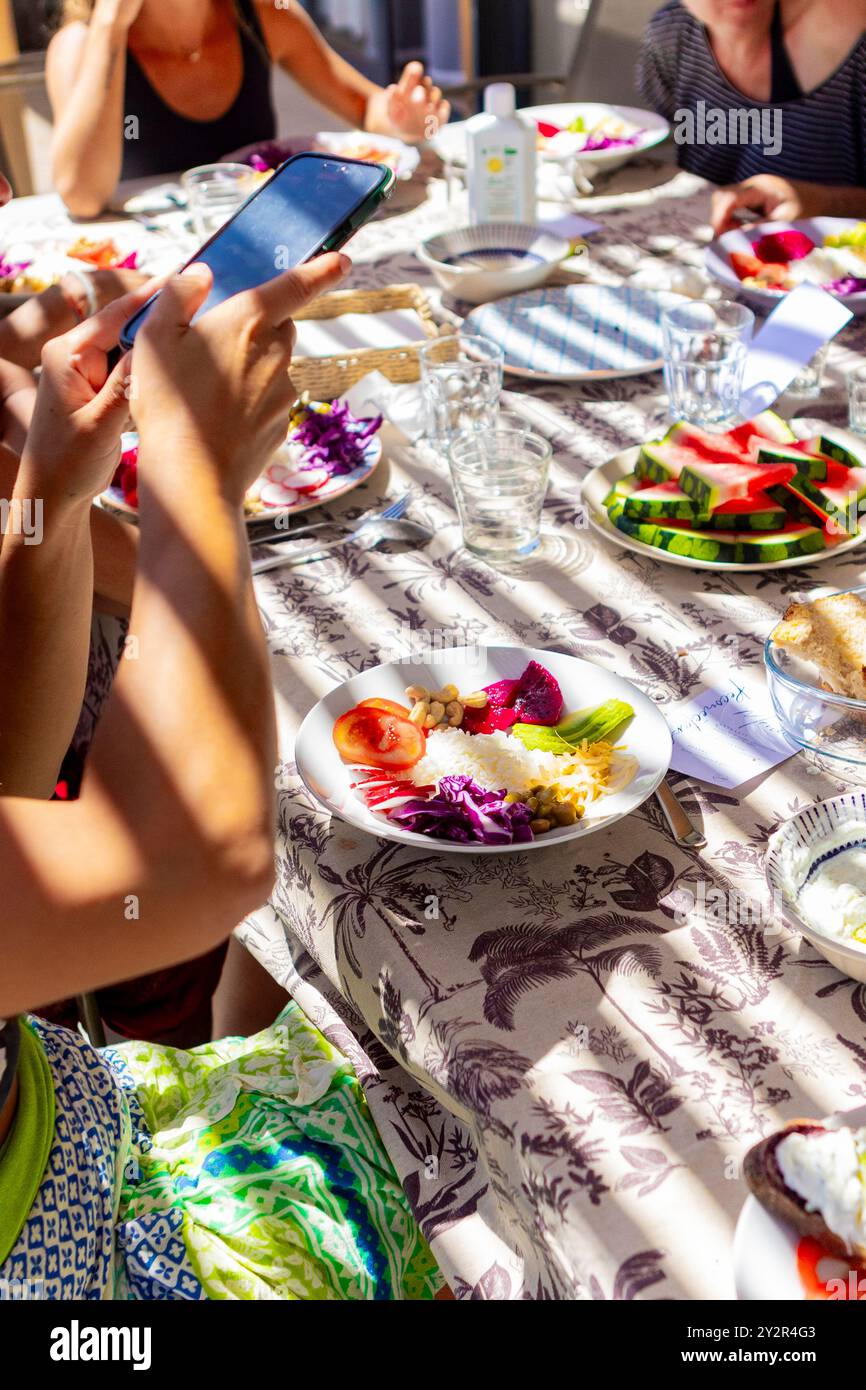 Eine Gruppe von Gästen in einem gesundheitsorientierten Rückzugsort genießt eine lebhafte Mahlzeit mit Wassermelonen-Gazpacho, veganem Poke und einer Vielzahl von frischen Gerichten unter dem Stockfoto