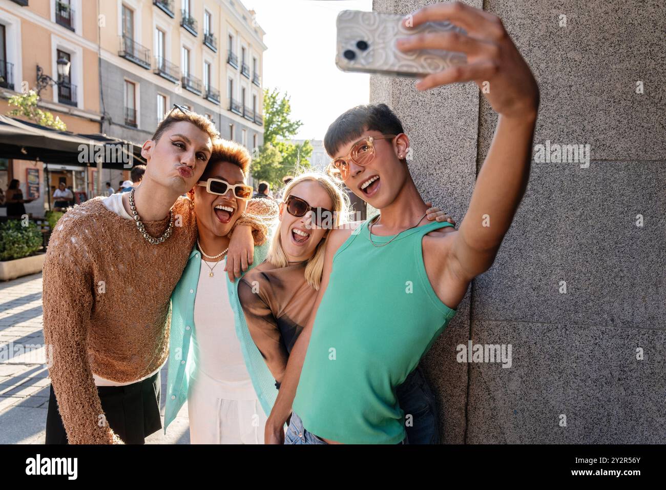 Eine Gruppe von LGBTQIA+ Freunden hält einen freudigen Selfie-Moment an einem sonnigen Tag in der Stadt fest, in der Nähe der von der Natur inspirierten Street Art in . Stockfoto