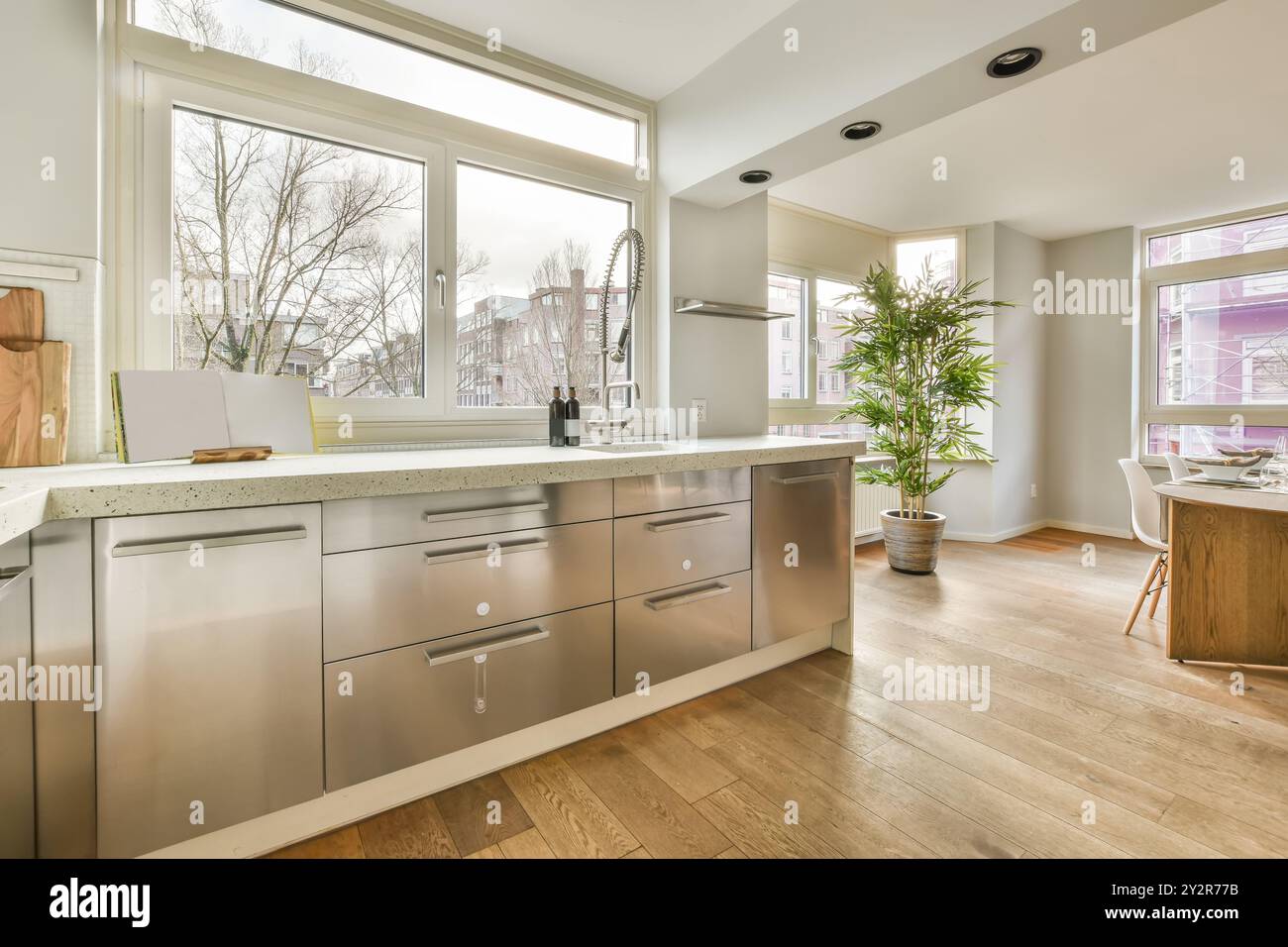 Eine geräumige Küche mit Edelstahlschränken, Hartholzböden und einem großen Fenster, das den Raum in natürliches Licht taucht. Stockfoto