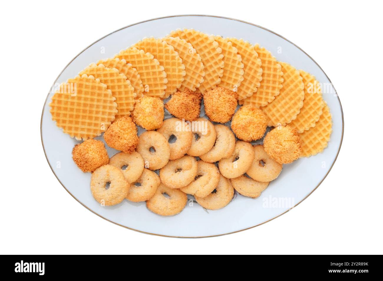 Verschiedene Backwaren und Waffeln in Keramikplatte isoliert auf weißem Hintergrund. Goldener romantischer Keks. Hausgemachte süße Nachspeise. Draufsicht. Stockfoto