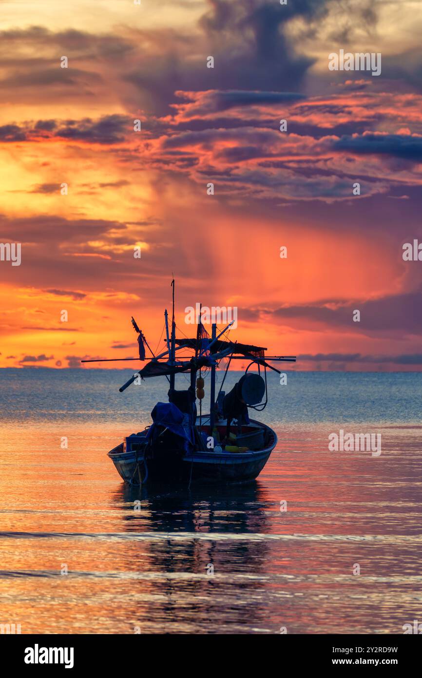 Farbenfroher Sonnenaufgangshimmel über dem traditionellen Fischerboot im tropischen Meer in Phetchaburi, Thailand Stockfoto