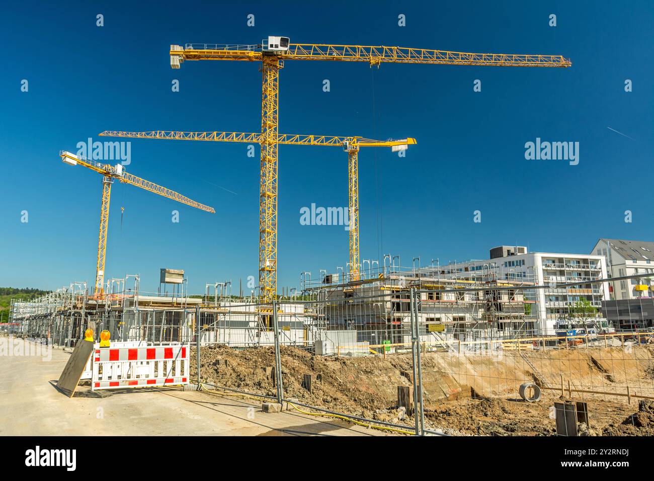 Große Baustelle mit Kränen, Zaunfundamenten und unfertigen Gebäuden Stockfoto