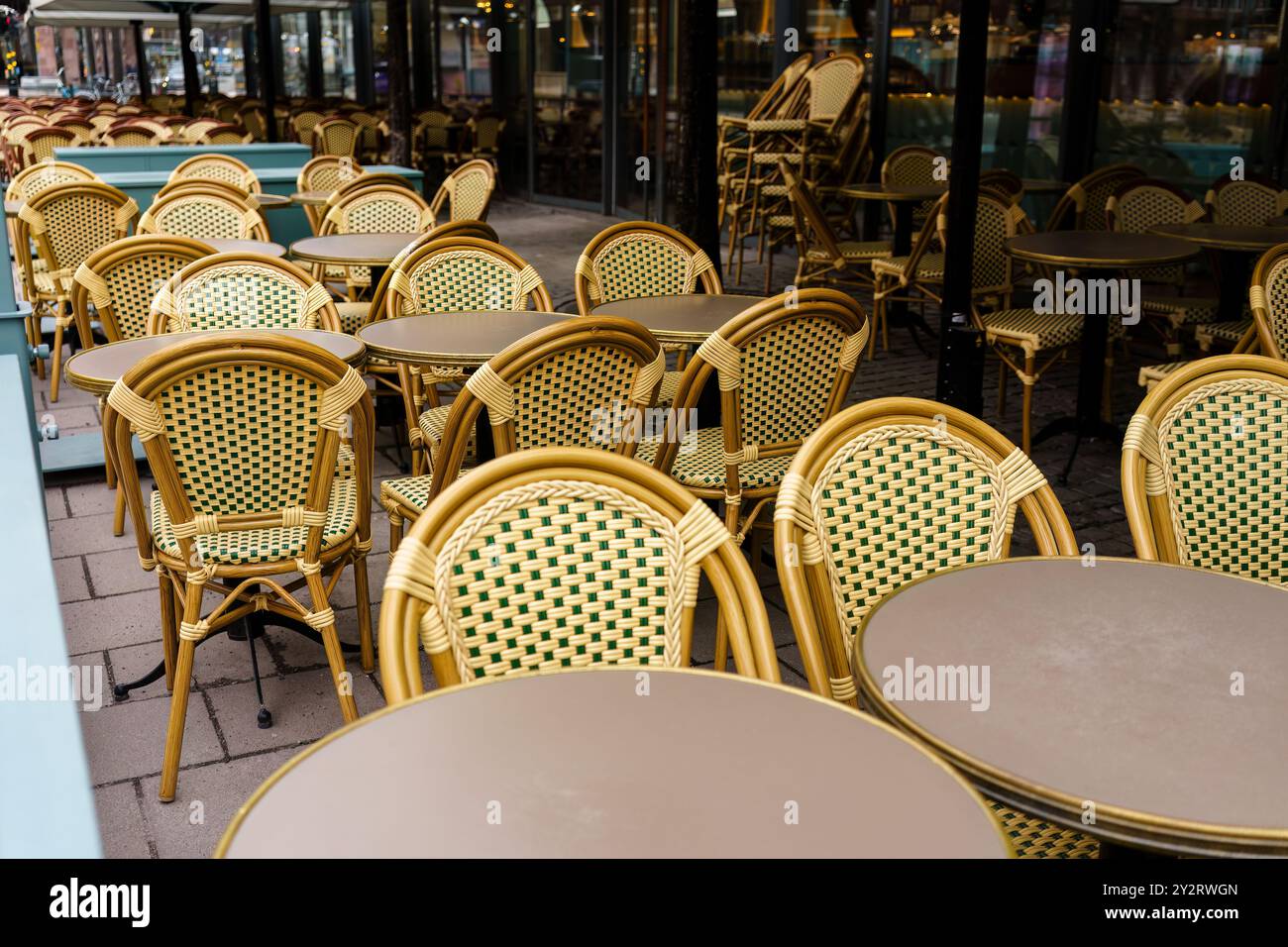 Leere Korbstühle und Tische im europäischen Café an einem bewölkten Tag Stockfoto