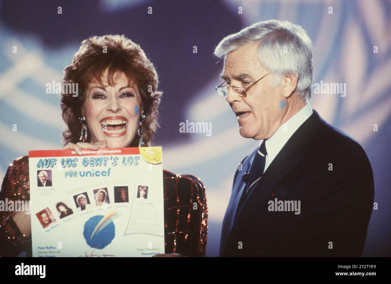 FOTOREPERTOIRE - Joachim Fuchsberger mit Caterina Valente in auf Los geht s los fÂ¸r UNICEF ARD 03/86 - Mann TV-Moderator Moderation Schauspieler Schauspiel TV stehen Saal Studio Kulisse Dekoration BÂ¸hne halb quer Gespr''°ch beide haben einen blauen Punkt auf der Wange blauer Punkt blau C. Valente h'°lt ein Plattencover hoch ein Cover hochhaltend Platte Langspielplatte LP fÂ¸r UNICEF Blacky (keine - 1986-03&01 www.imago-images.de/ipa -agency.net) via imago ps das Foto kann in Übereinstimmung mit dem Kontext verwendet werden, in dem es aufgenommen wurde, und ohne diffamierend zu sein Stockfoto