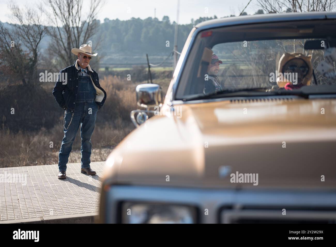 Detail eines typisch amerikanischen Charakters mit Jeans, Lederstiefeln, Sonnenbrille und Strohhut neben seinem klassischen Pickup-Truck Stockfoto