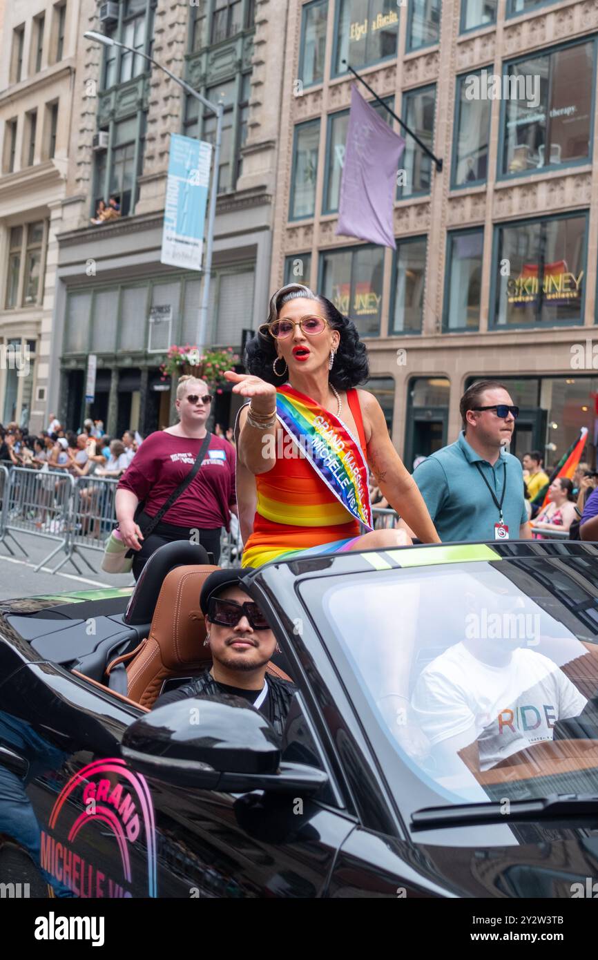 Eine pulsierende Szene einer Stolz-Parade mit einer großen Marschall Michelle Visage, die aus einem Cabrio winkt, umgeben von Zuschauern in einer urbanen Umgebung. Stockfoto