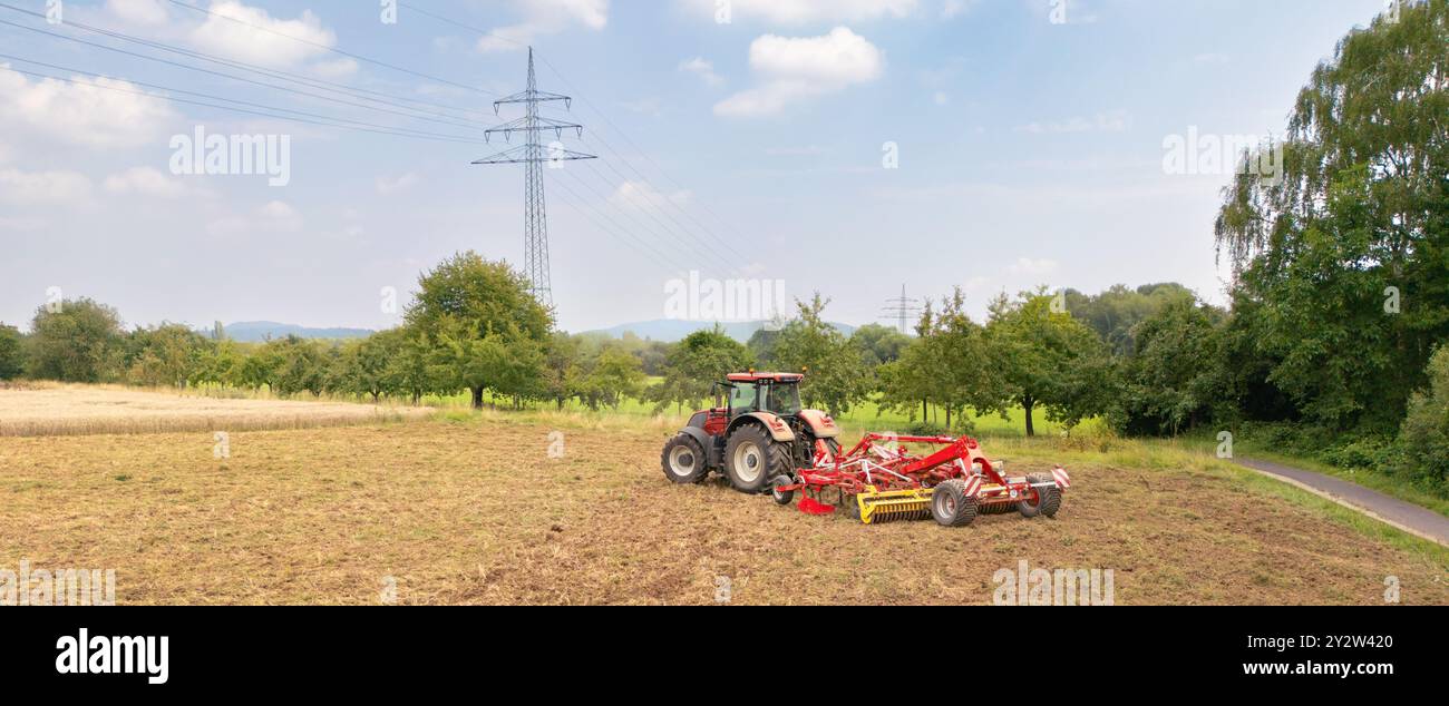Rückansicht eines roten Traktors auf dem Feld, auf dem Land, mit den Antriebssträngen im Hintergrund an einem sonnigen Sommertag Stockfoto