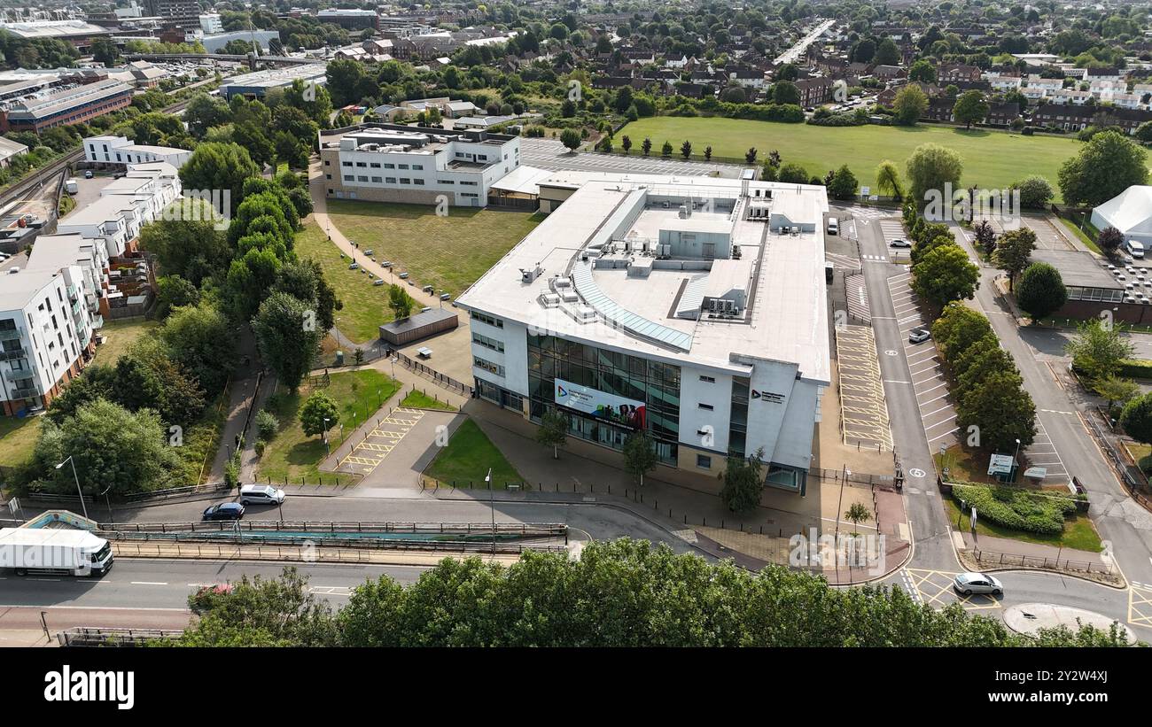 Blick aus der Vogelperspektive auf ein modernes Bildungsgebäude, umgeben von Grün und Wohngebieten in einer Vorstadtlage. Stockfoto