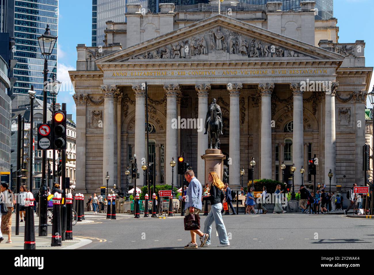 Zwei Leute überqueren die Straße an der Bank Junction vor der Westfassade der Royal Exchange, City of London, London, UK Stockfoto