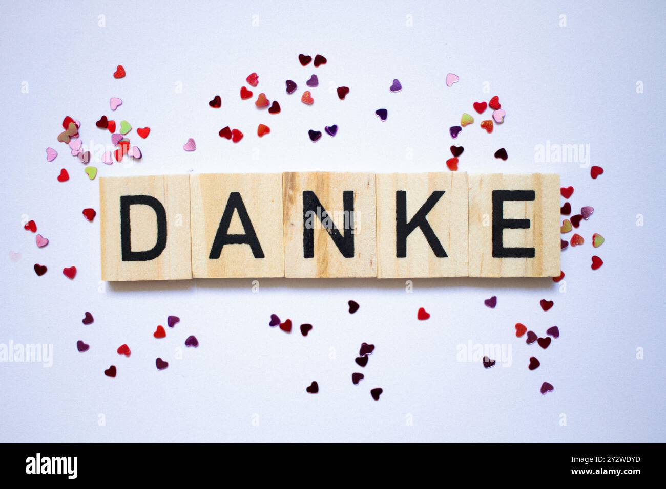 Dankeskarte in deutscher Sprache, Dankestext, kleine kleine, glänzende Herzen um Scrablle Buchstaben herum Stockfoto