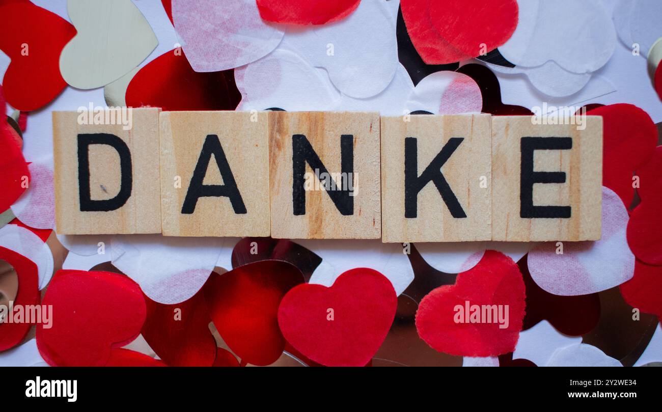 Dankeskarte in deutscher Sprache mit Wort DANKE auf Scrabble-Blöcken und Hintergrund aus Herzen Stockfoto