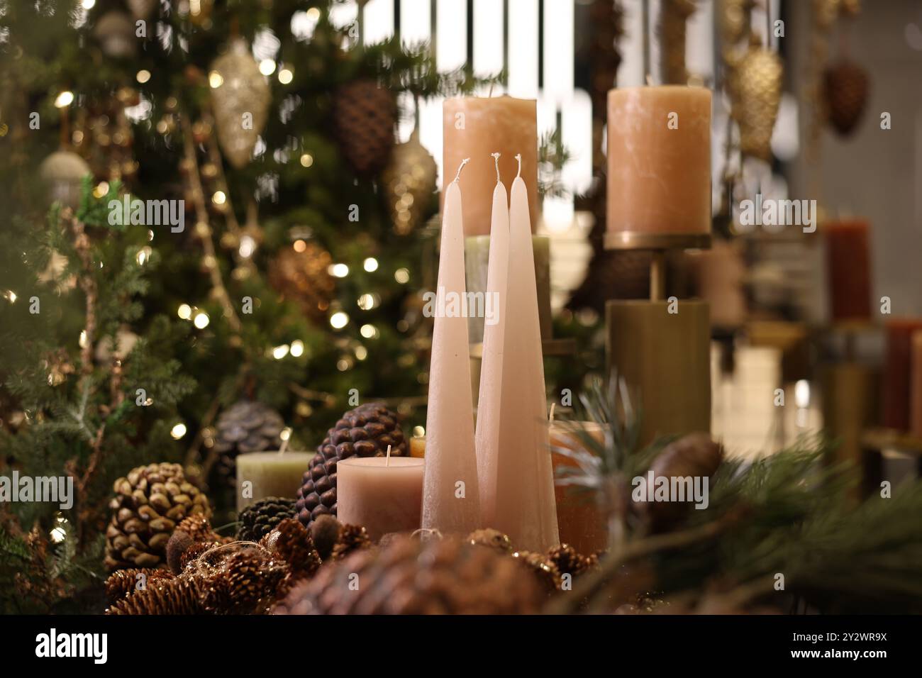 Eine Nahaufnahme von drei Kerzen mit festlicher Weihnachtsdekoration im verschwommenen Hintergrund Stockfoto