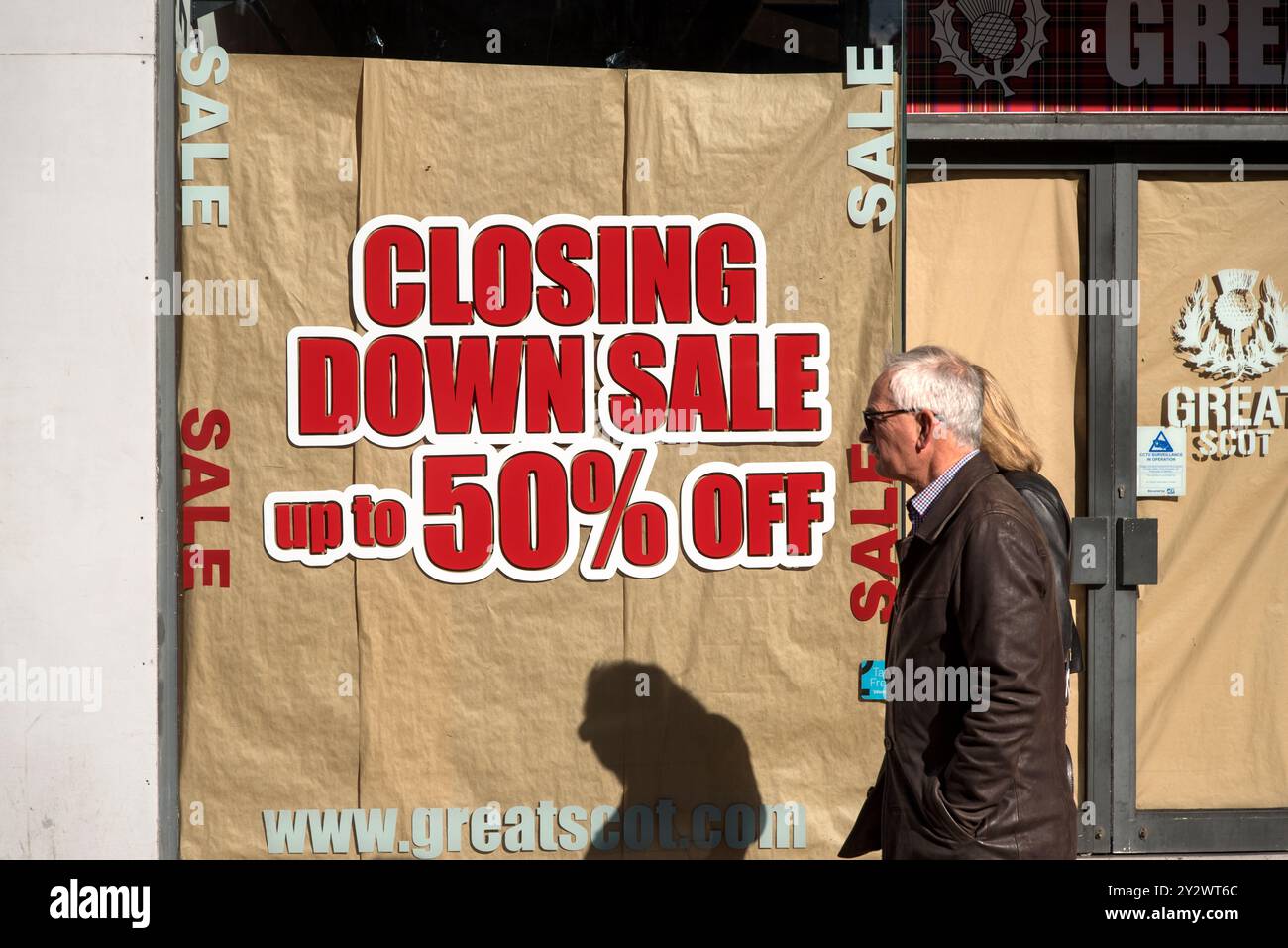 Ein älteres Ehepaar läuft an einem Verkaufsschild an einem Schaufenster in der Princes Street, Edinburgh, Schottland, U vorbei Stockfoto