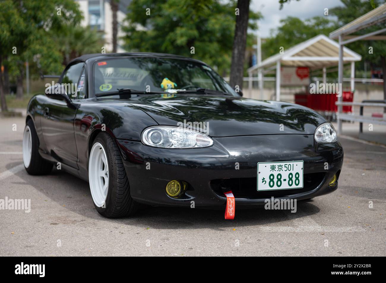 Mazda MX-5 Miata NB, zweite Generation, schwarz. Er ist mit weißen Rädern, gelbem Spoiler und Nebelleuchten abgestimmt. Stockfoto