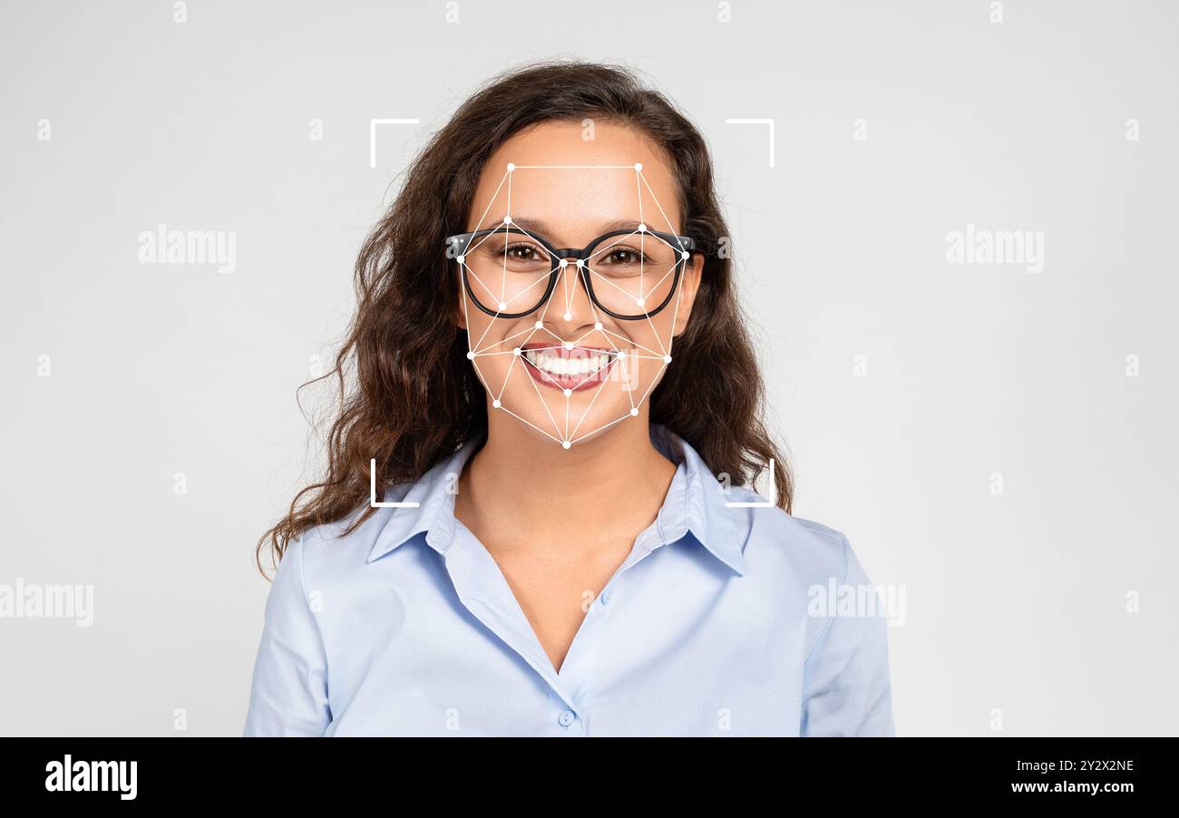 Frau lächelt mit einer Brille in einem Studio und stellt Gesichtserkennungstechnologie vor Stockfoto