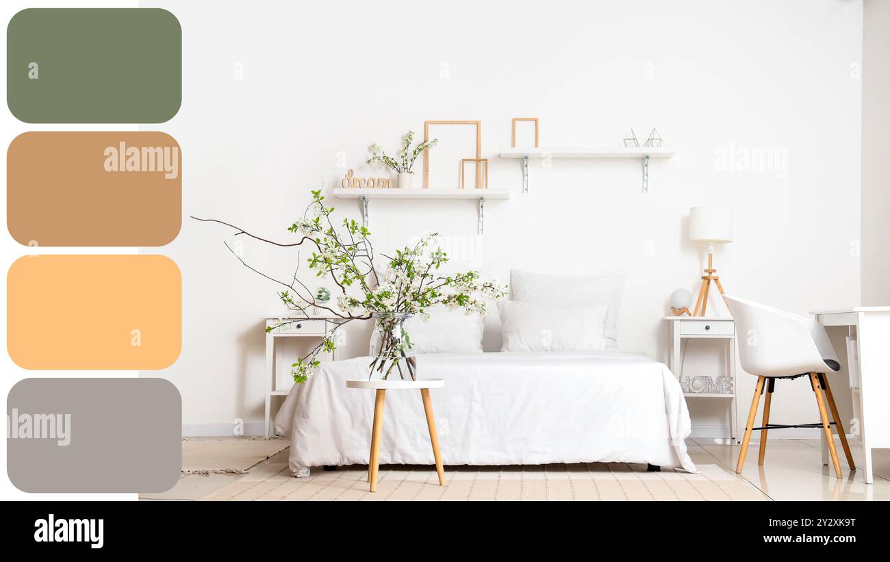 Vase mit blühenden Zweigen auf dem Tisch neben dem gemütlichen Bett im weißen Schlafzimmer. Verschiedene Farbmuster Stockfoto