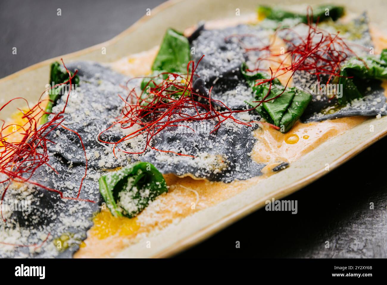 Gourmet-Tintenfisch-Ravioli mit lebhaften Garnituren in einer cremigen Sauce - ein elegantes und künstlerisches Gericht Stockfoto
