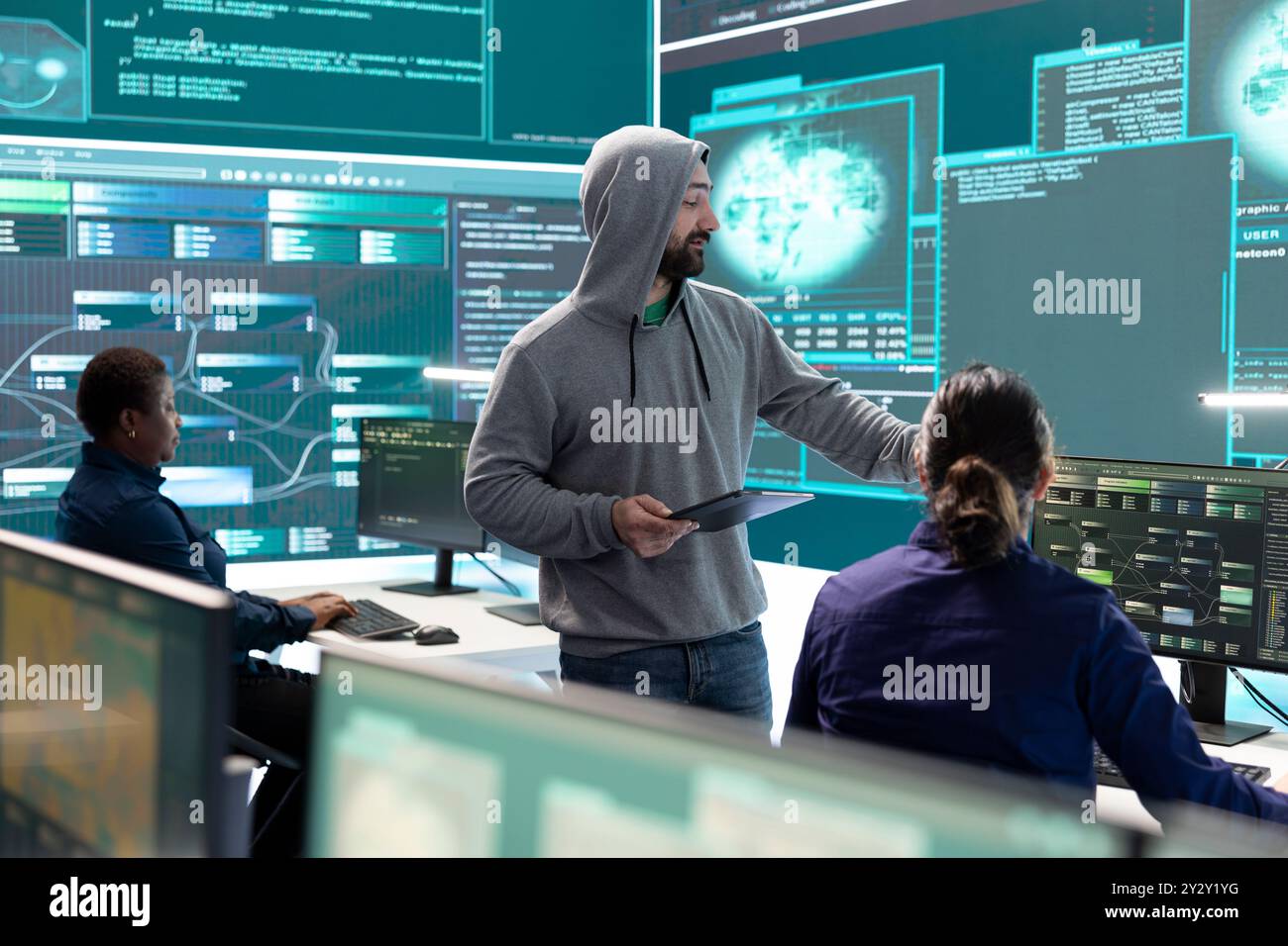 Staatliche Hacker analysieren Daten zur Erkennung von Cyberbedrohungen und schauen sich einen großen Bildschirm in High-Tech-Büros an. Heben Sie Cyber Intelligence, Online-Sicherheit und die Verhinderung digitaler Bedrohungen hervor. Stockfoto