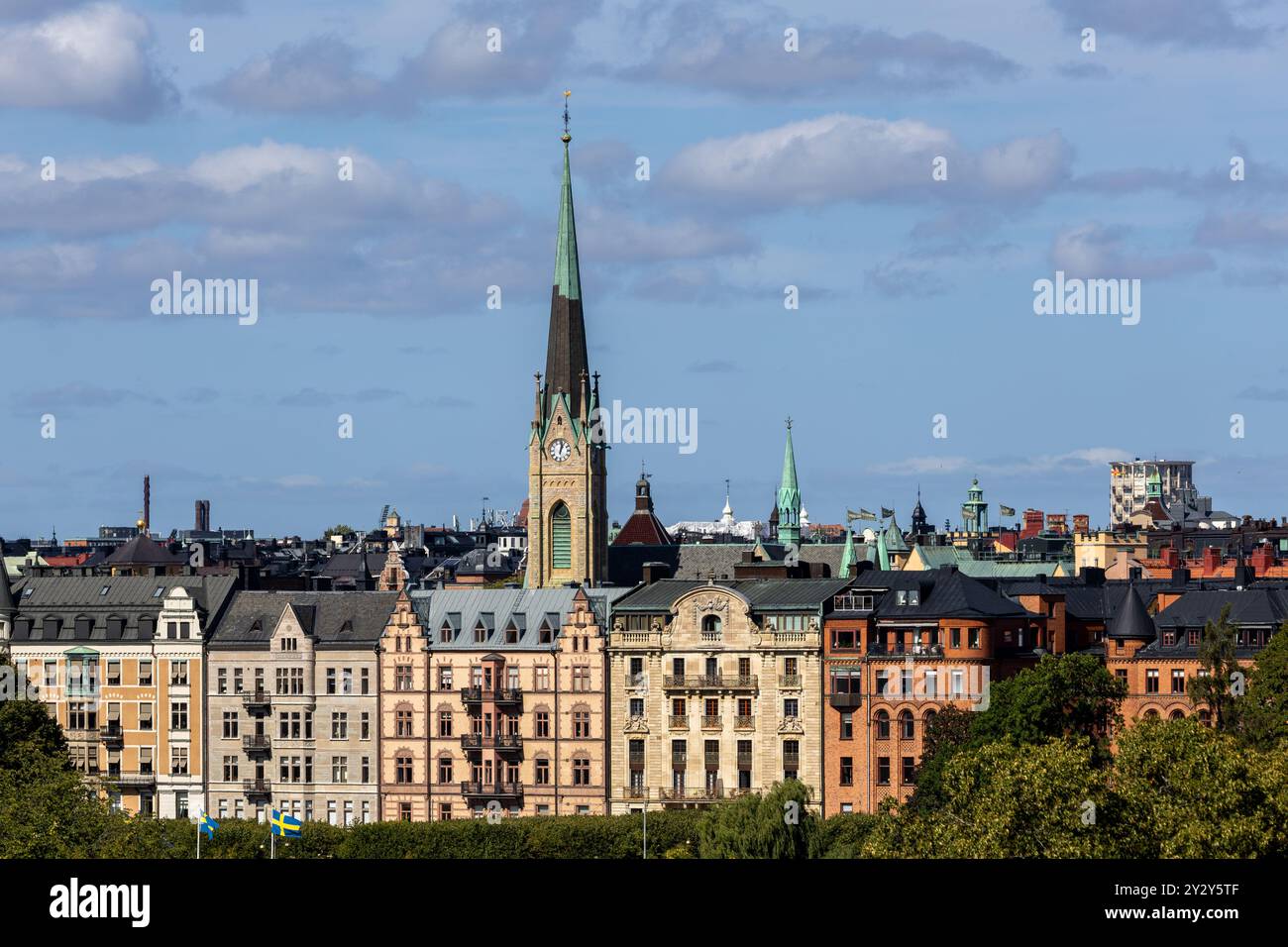 Ein Panoramablick auf eine Skyline der Stadt mit einem markanten Kirchturm und einer Mischung aus historischer und moderner Architektur unter teilweise bewölktem Himmel. Stockfoto