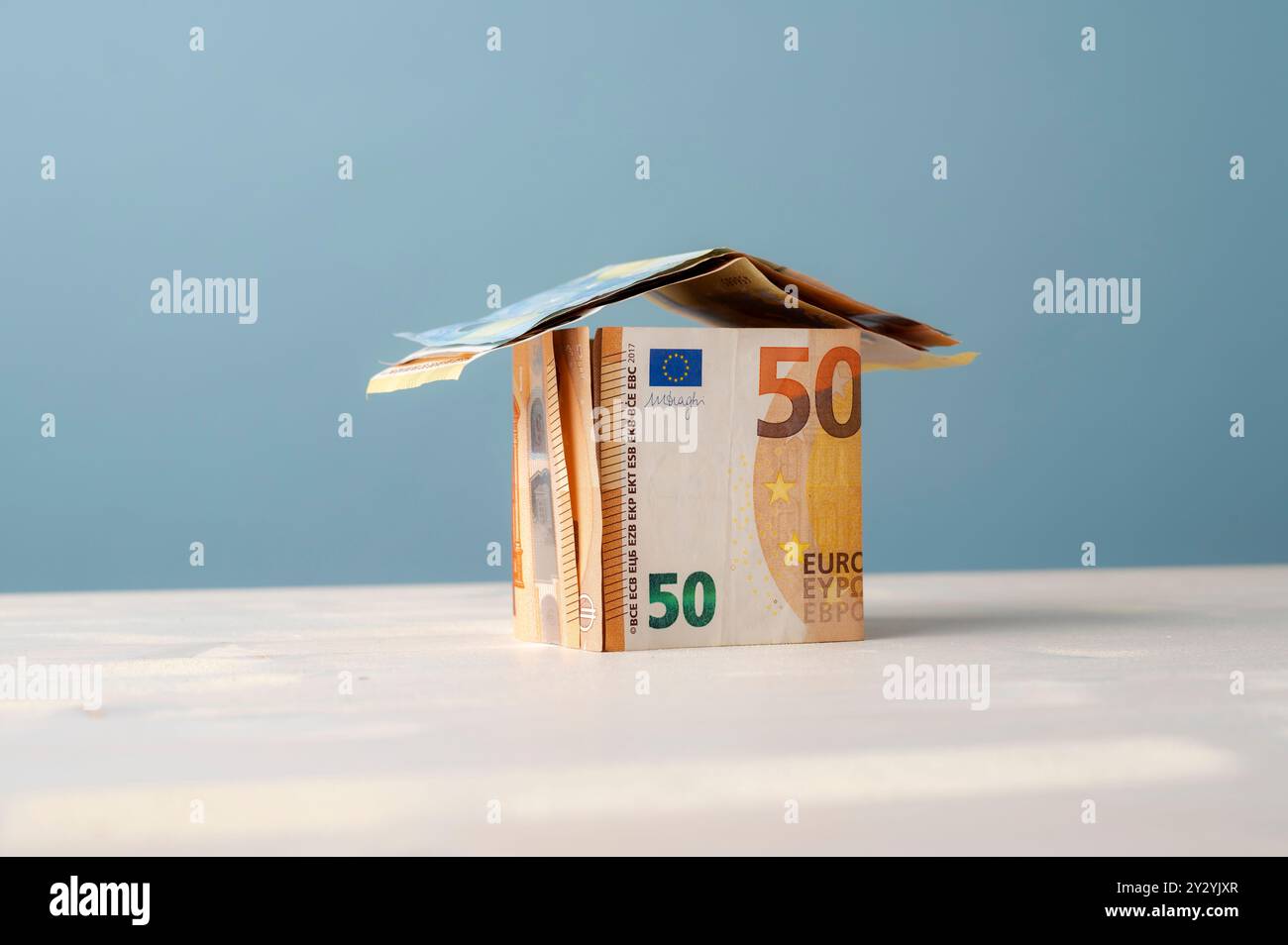 Konzeptionelles Bild von Immobilien, Hypotheken, Mieten und Wohngebäuden. Haus aus Euro-Banknoten auf blauem Hintergrund mit Kopierraum. Stockfoto