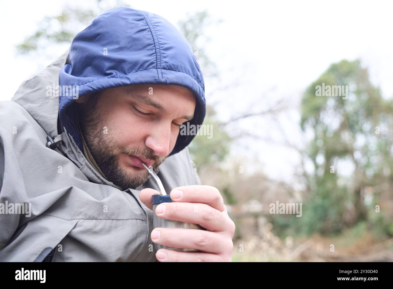 Junger argentinischer Mann trinkt Mate, ein traditionelles Heißgetränk, an einem kalten Wintermorgen. Sein Gesicht spiegelt das Gefühl des Wohlbefindens und des Wohlbefindens wider Stockfoto