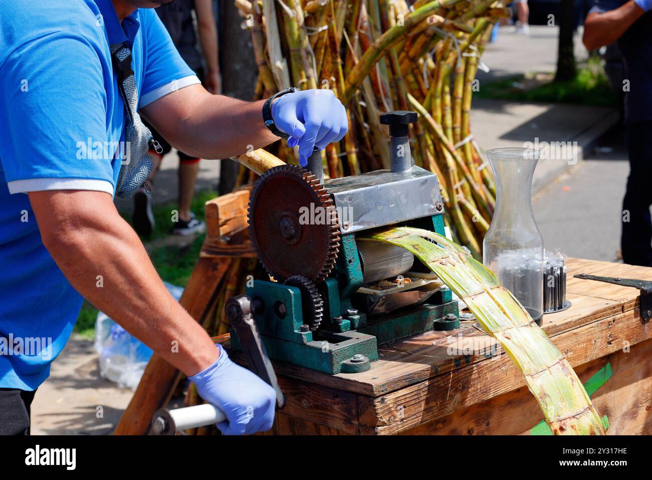 Eine Person dreht einen manuellen Entsafter der Zuckerrohrmühle mit der Hand, um Zuckerrohrsaft zu extrahieren Stockfoto