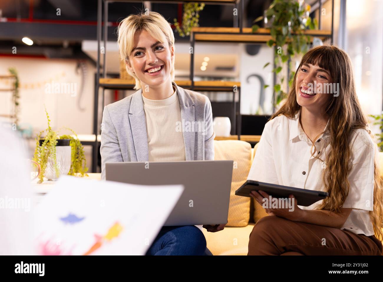 Über kreatives Schreibgeschäft, lächelnde Frauen mit Laptop und Tablet im Büro Stockfoto