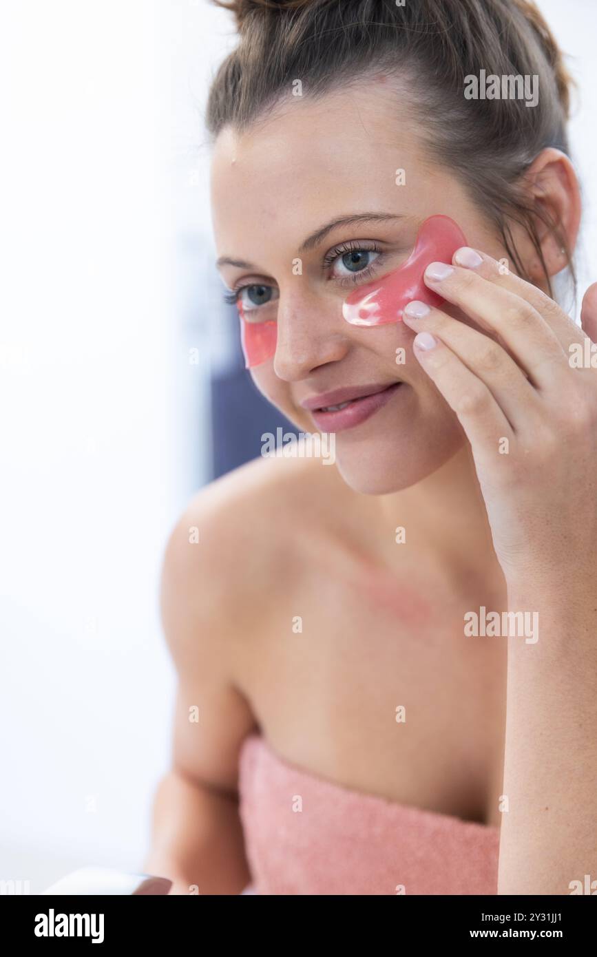 Anwendung von Pflastern unter den Augen, junge Frau, die zu Hause eine Spa-Behandlung genießt Stockfoto