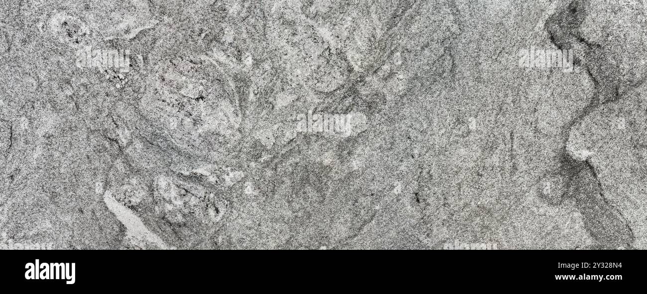Graue natürliche Granitplatte. Zufälliges Welligkeitsmuster, mit einigen dunklen Adern. Granit ist ein gewöhnlicher Naturstein, der in vielen Arbeitsflächen verwendet wird Stockfoto