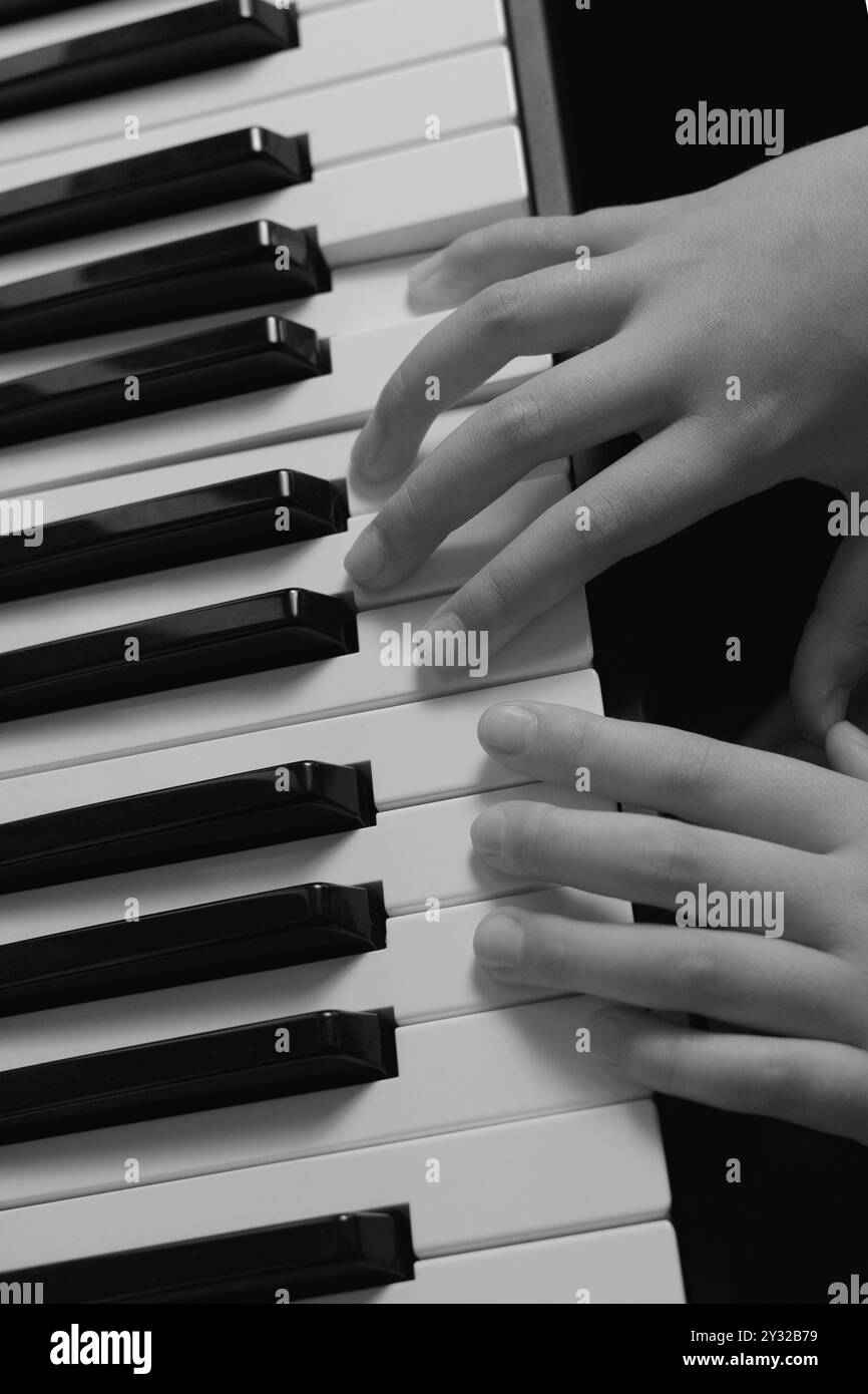 Klavierspielpraxis. Schwarzweiß-Nahaufnahme. Musikunterricht. Synthesizer-Tastatur. Notizen und Skalen. Stockfoto
